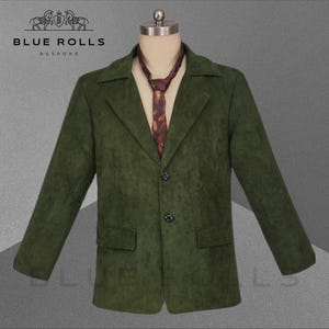 May include: A green suede blazer with a three-button fastening and a pocket on the left side. The blazer is worn over a patterned tie.