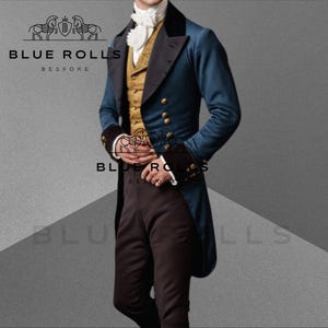 Könnte beinhalten: Ein Mann trägt einen blauen Frack mit goldenen Knöpfen, eine goldene Weste und eine schwarze Hose. Der Frack hat einen schwarzen Samtkragen. Der Mann steht vor einem grauen Hintergrund. Der Text "BLUE ROLLS BESPOKE" ist im Bild sichtbar.