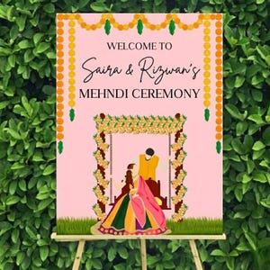 May include: A pink sign with the words "WELCOME TO Saira & Rizwan's MEHNDI CEREMONY" in black script. The sign features a floral arch and a couple in traditional attire, with a green leafy background.