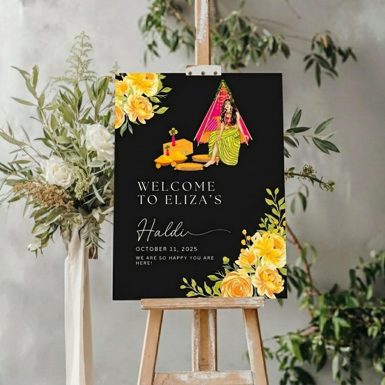 May include: A black sign on an easel with the text "WELCOME TO ELIZA'S Haldi OCTOBER 11, 2025 WE ARE SO HAPPY YOU ARE HERE!". The sign features yellow floral accents and an illustration of a woman in traditional attire.