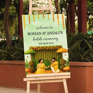 May include: A wooden easel displays a sign with the text "welcome to ROHAN & ANJALI'S haldi ceremony 5th April 2024." The sign features a watercolor illustration of a couple in yellow attire, with floral and umbrella decorations.