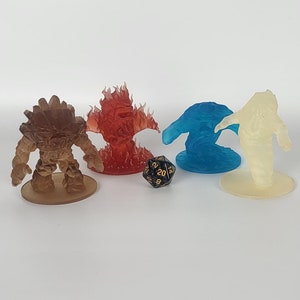 Puede incluir: Cuatro figuritas en miniatura de criaturas elementales, un elemental de tierra marrón, un elemental de fuego rojo, un elemental de agua azul y un elemental de aire blanco, sobre un fondo blanco. Un dado negro y dorado está en el centro de la imagen.