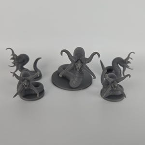 May include: Five gray miniature fantasy creatures. The central figure is a serpent-like creature with an octopus-like head, surrounded by four similar figures. The figures are on small circular bases.