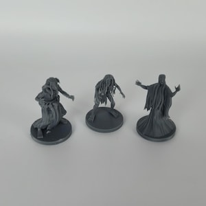 May include: Three gray 3D printed miniature figures of ghostly creatures. The figures are standing on round bases.