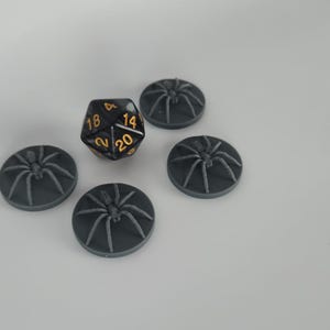 May include: Five black plastic spider bases with a black and gold twenty-sided die in the center.