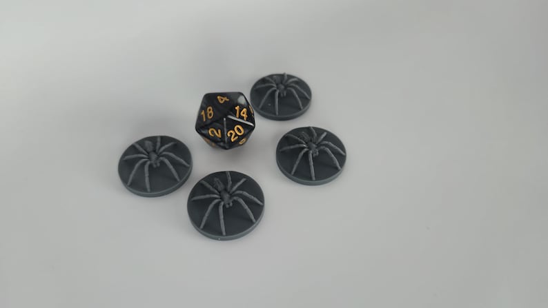 May include: Five black plastic spider bases with a black and gold twenty-sided die in the center.