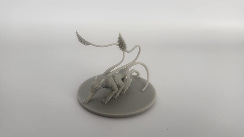 以下が含まれることがあります： 長い細い尻尾と4本の脚を持つ生き物のグレーの3Dプリントミニチュア。生き物はしゃがみこんだ姿勢で、頭を下げている