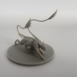以下が含まれることがあります： 人間型の胴体と猫のような体を持つ生き物のグレーの3Dプリントミニチュア。生き物は、スパイクのある長いセグメント化された尾を持ち、しゃがんだ姿勢をとっています。
