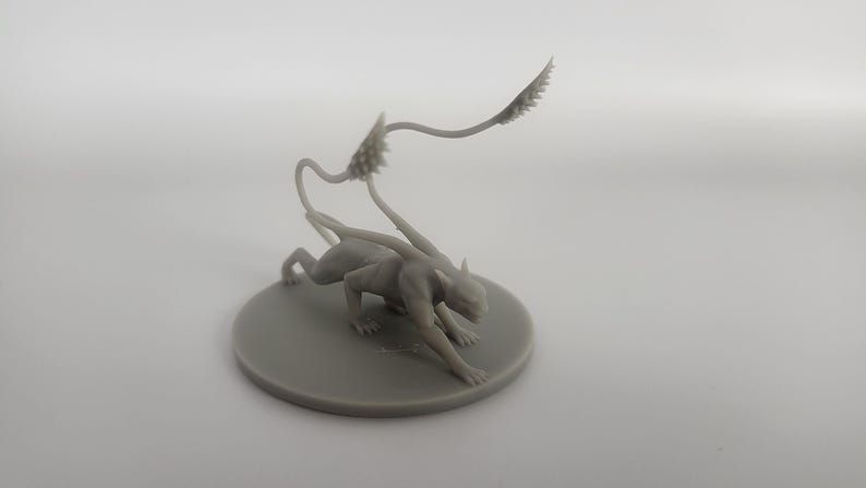 以下が含まれることがあります： 人間型の胴体と猫のような体を持つ生き物のグレーの3Dプリントミニチュア。生き物は、スパイクのある長いセグメント化された尾を持ち、しゃがんだ姿勢をとっています。