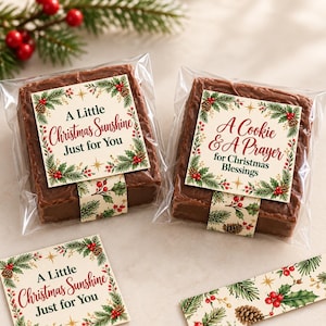 May include: Two square chocolate brownies individually wrapped in clear plastic, each featuring a decorative paper label with a Christmas holly, pine cone, and berry border. One label reads A Little Christmas Sunshine Just for You, the other A Cookie & A Prayer for Christmas Blessings.