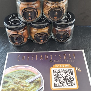 May include: Five small glass jars with black lids and labels that say "Chez Fadis" and "Thank you". The jars contain various spices and herbs. A card with the text "Chez Fadis DIY Magic Sauce" and a QR code is in the foreground.