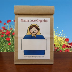 May include: A brown paper bag with a label that says "Mama Love Organics". The label features a cartoon illustration of a woman with a yellow headscarf and a blue dress holding a blank white sign. The text "www.mamaloveproducts.com" is printed below the illustration.