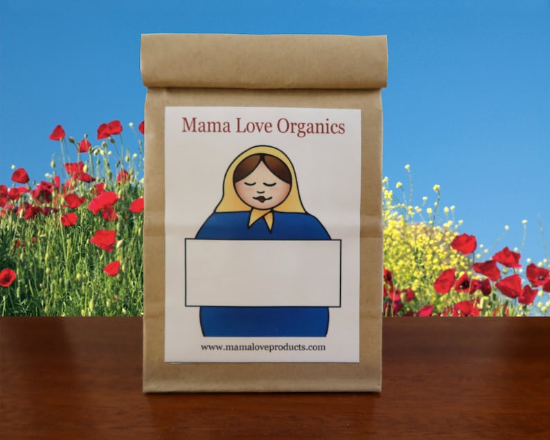 May include: A brown paper bag with a label that says "Mama Love Organics". The label features a cartoon illustration of a woman with a yellow headscarf and a blue dress holding a blank white sign. The text "www.mamaloveproducts.com" is printed below the illustration.