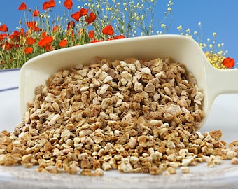 May include: A close-up shot of a white scoop overflowing with light brown, irregularly shaped pieces. The scoop is set against a backdrop of red poppies and yellow wildflowers under a blue sky. The pieces appear to be dried herbs or spices.