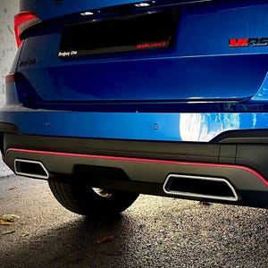 Könnte beinhalten: Rückansicht eines blauen Autos mit schwarzen Akzenten und roten Zierleisten. Das Auto hat eine Doppelrohrauspuffanlage mit verchromten Endrohren. Die Buchstaben "RS" sind rot sichtbar.