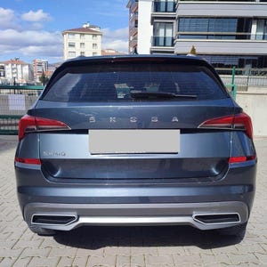 Può includere: Vista posteriore di un SUV grigio scuro. Il veicolo ha fanali posteriori rossi, un paraurti argentato e il nome "KAMIQ" è visibile. Il logo Skoda è sopra l'area della targa.