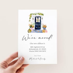 May include: A watercolor-style moving announcement card. The card features a navy blue front door with floral arrangements and pumpkins. The text reads "We've moved!" and includes the new address and contact information. Signed "love from Michael & Emily."