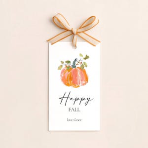 May include: A rectangular white gift tag featuring a watercolor illustration of an orange pumpkin with green leaves and stems. The text reads Happy FALL and love, Grace in black font. A beige and orange striped ribbon is tied in a bow at the top.