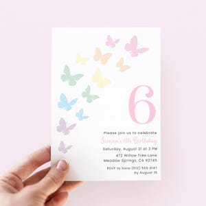Pode incluir: Um cartão de convite branco com borboletas em tons pastel e o número 6. O texto diz "Please join us to celebrate Sienna's 6th Birthday" com detalhes do evento. Segurado por uma mão.