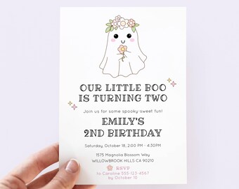 May include: A white invitation card with a cute ghost illustration wearing a flower crown and holding a flower. The text reads "OUR LITTLE BOO IS TURNING TWO" and "EMILY'S 2ND BIRTHDAY". Includes event details.