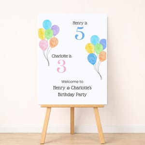 May include: A white rectangular birthday party sign featuring watercolor illustrations of colorful balloons. The text reads Henry is 5, Charlotte is 3, and Welcome to Henry & Charlotte's Birthday Party. The sign is displayed on a wooden easel.