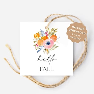 May include: A white square tag with a watercolour floral design featuring orange pumpkins and a pink flower. The words "hello FALL" are written in black script. A brown tag with the words "INSTANT DOWNLOAD 2 sizes included" is attached.