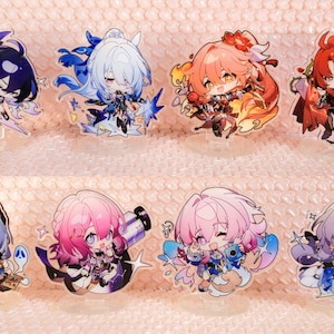 May include: Set of ten anime character acrylic stands. The characters are all female and have colourful hair and outfits. The stands are clear and have a white background. The text "ACGcrafts" appears on two of the stands.