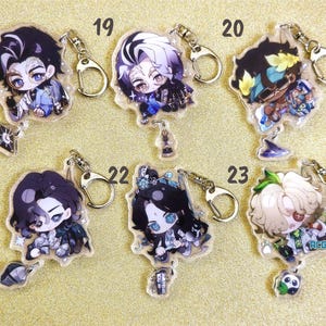 May include: Six colorful anime character keychains with glitter accents. Each keychain features a different character with unique details and a silver metal ring.