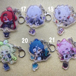 May include: A collection of six anime-style acrylic keychains. Each keychain features a colorful character design with a silver-colored clasp and a small charm. The keychains are numbered 16 through 21.