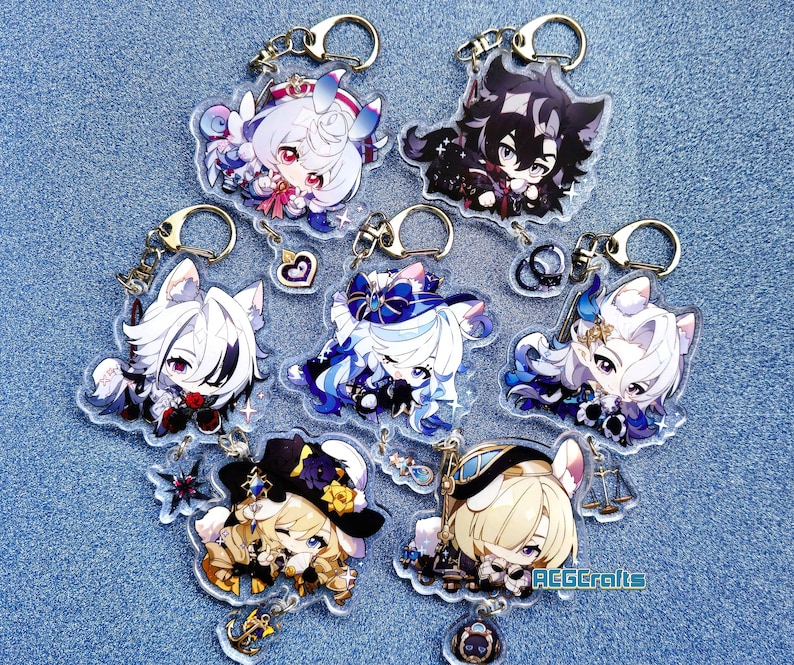 May include: Seven colorful anime character keychains with gold key rings. Each keychain features a different character with a unique design and color scheme. The keychains are made of clear acrylic and have a glossy finish.