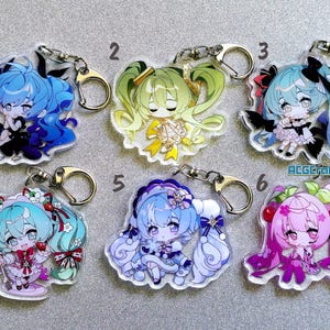 May include: Six colorful keychains featuring anime-style characters with long hair and different outfits. The keychains are made of clear acrylic and have silver metal key rings.
