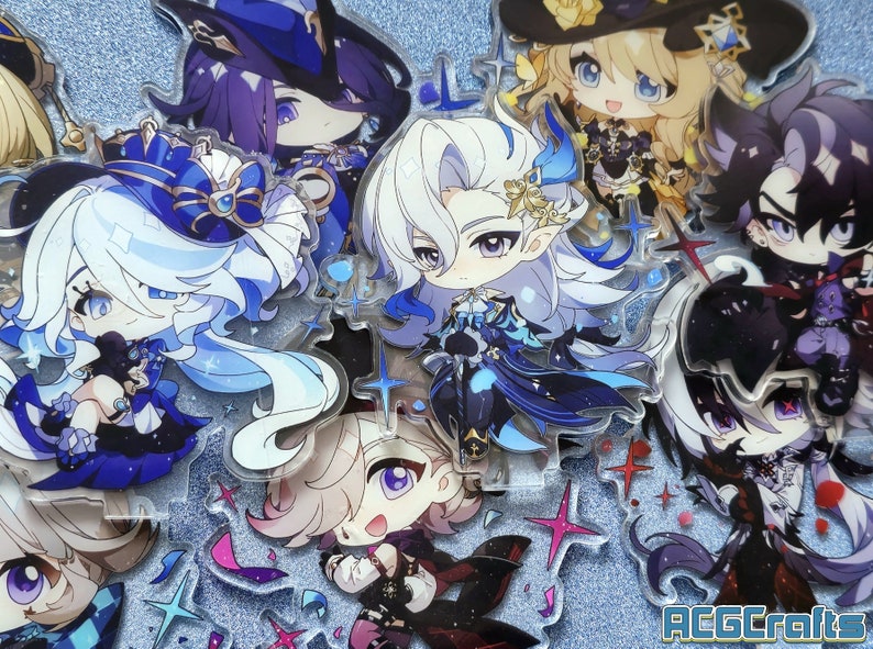 May include: A collection of eight anime-style character acrylic charms. The charms are all different characters with various colors and designs. The characters are all in a chibi style, with large heads and small bodies. The charms are all on a sparkly blue background.