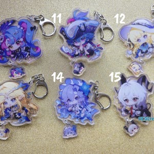 May include: A collection of anime-style acrylic keychains featuring various characters with detailed designs. Each keychain has a silver-colored keyring and a small charm. The characters have colorful hair and outfits.