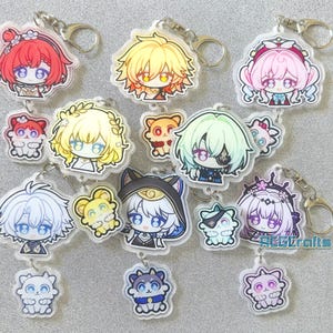 Könnte beinhalten: Eine Sammlung von Acryl-Schlüsselanhängern mit verschiedenen Anime-Charakterköpfen und kleinen tierischen Begleitern. Jeder Anhänger verfügt über einen Metallring. Die Figuren zeigen diverse Haarfarben wie Rot, Gelb, Rosa, Weiß und Grün.