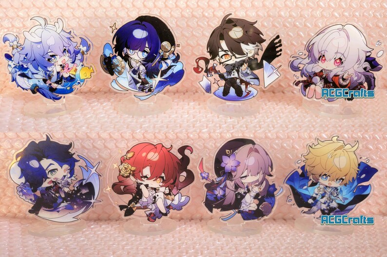 May include: Set of ten anime character acrylic charms. The charms feature various characters with different coloured hair and clothing. The characters are all smiling and have large eyes. The charms are attached to clear acrylic stands.