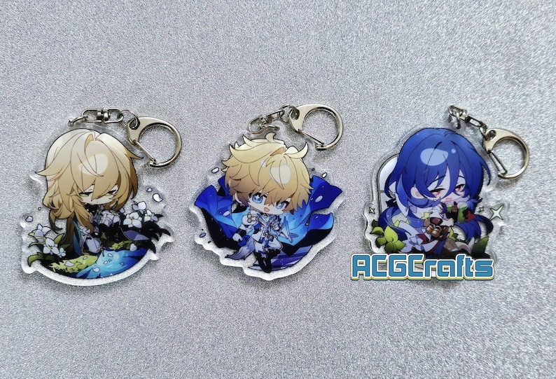 Op de afbeelding: Drie anime-personage sleutelhangers met transparante acryl achtergronden. De personages zijn een blonde jongen met blauwe ogen, een blonde jongen met blauwe ogen en een jongen met blauw haar en blauwe ogen. De sleutelhangers liggen op een grijs oppervlak. De tekst "ACGCrafts" is zichtbaar in de rechter benedenhoek van de afbeelding.