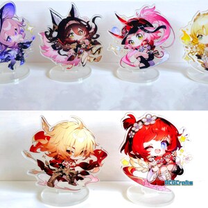 May include: Set of 6 anime character acrylic stands. The stands feature characters with different coloured hair and outfits. The characters are all in a chibi style, with large heads and small bodies. The stands are made of clear acrylic and have a circular base.