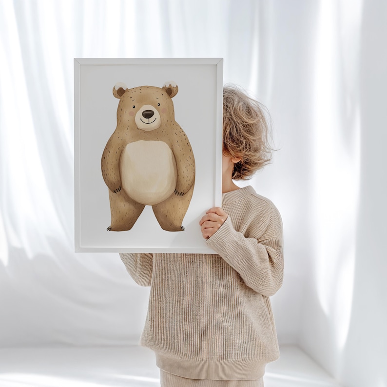 May include: A framed print featuring a friendly cartoon bear illustration. The bear is depicted in shades of brown and beige with a light-colored belly. The artwork is set against a white background, and the frame is also white.