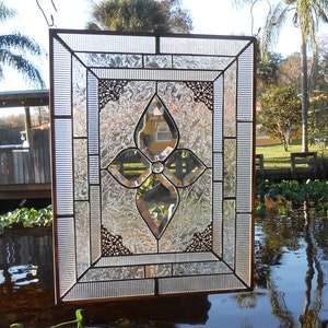 May include: A stained glass window panel with a clear glass design featuring a four-leaf clover motif. The window is framed in a brown wood frame and has a rustic look.