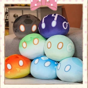 Puede incluir: Una colección de peluches esféricos de varios colores, incluyendo naranja, verde, azul y morado. Cada peluche tiene dos ojos grandes y circulares y una boca circular más pequeña. Los juguetes están apilados, creando una exhibición juguetona y colorida.