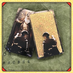 May include: Two rectangular acrylic charms. One features a detailed illustration of a person with blue hair, and the other has a gold glitter design. The charms are set against a green background with Chinese characters.