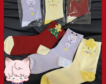 May include: Assorted socks in various colors, including red, yellow, and lavender. Each sock features a unique design, such as a bunny, a clover, or a Christmas tree. The socks are packaged in clear plastic and are displayed on a black surface.