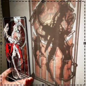 May include: A clear acrylic dragon figurine with red and white accents, held in front of a stained-glass window. The window features a dark silhouette of a similar dragon design, creating a shadow effect. The artwork has a fantasy theme.