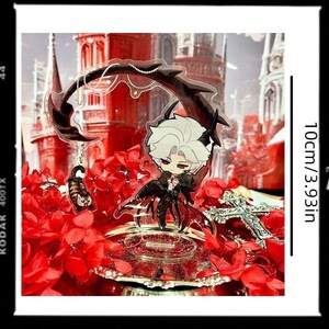 May include: A clear acrylic anime-style figure of a character with white hair and black attire, adorned with a decorative black arch and a small charm. The figure is set against a backdrop of red flowers and a gothic-style building. The figure is 3.93 inches (10cm) tall.