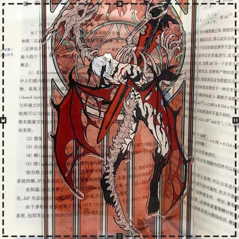 May include: A clear acrylic standee featuring a detailed illustration of a winged demon with red and black accents. The artwork depicts a figure with white hair and a skeletal design, set against a backdrop of text and a stained-glass-like pattern.