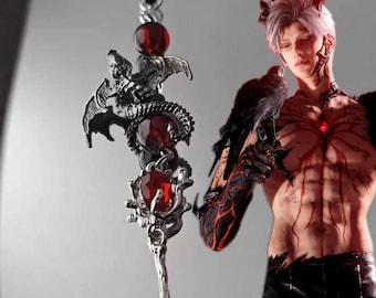 May include: A silver-colored fantasy staff with red gemstone accents and a dragon-like figure. The staff is suspended from a black cord. The staff is a gothic-style accessory.