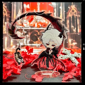 May include: A clear acrylic anime figure featuring a character with white hair, red eyes, and a black and red outfit. The figure is on a clear stand with a cat charm and a decorative scythe. Red flowers and a cross are in the background.