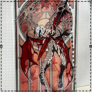 May include: A clear acrylic standee featuring a detailed illustration of a winged demon with red wings and a skeletal spine. The artwork has a gothic theme with a red and orange stained-glass style background.