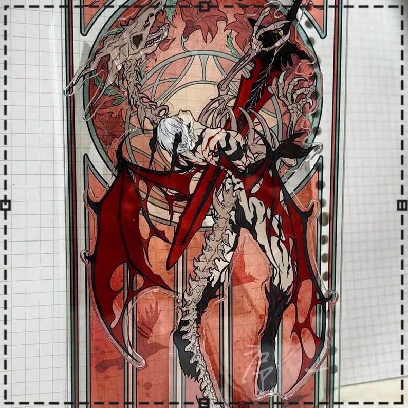 May include: A clear acrylic standee featuring a detailed illustration of a winged demon with red wings and a skeletal spine. The artwork has a gothic theme with a red and orange stained-glass style background.