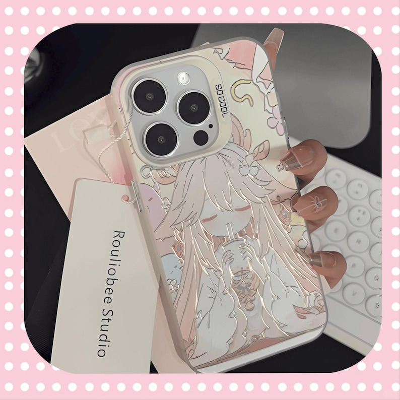 Może przedstawiać: Przezroczyste etui na telefon z kresk&oacute;wkowym wzorem anime dziewczyny w odcieniach r&oacute;żu i bieli. Etui ma napis "SO COOL" i nazwę marki "Rouliobee Studio" na etykiecie. Etui jest przeznaczone do telefonu z wieloma obiektywami.